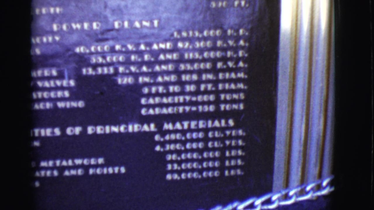 Close 8mm view of a power plant plaque with capacity and materials text, partially blurred by handheld filming.