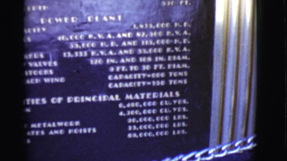 Close 8mm view of a power plant plaque with capacity and materials text, partially blurred by handheld filming.