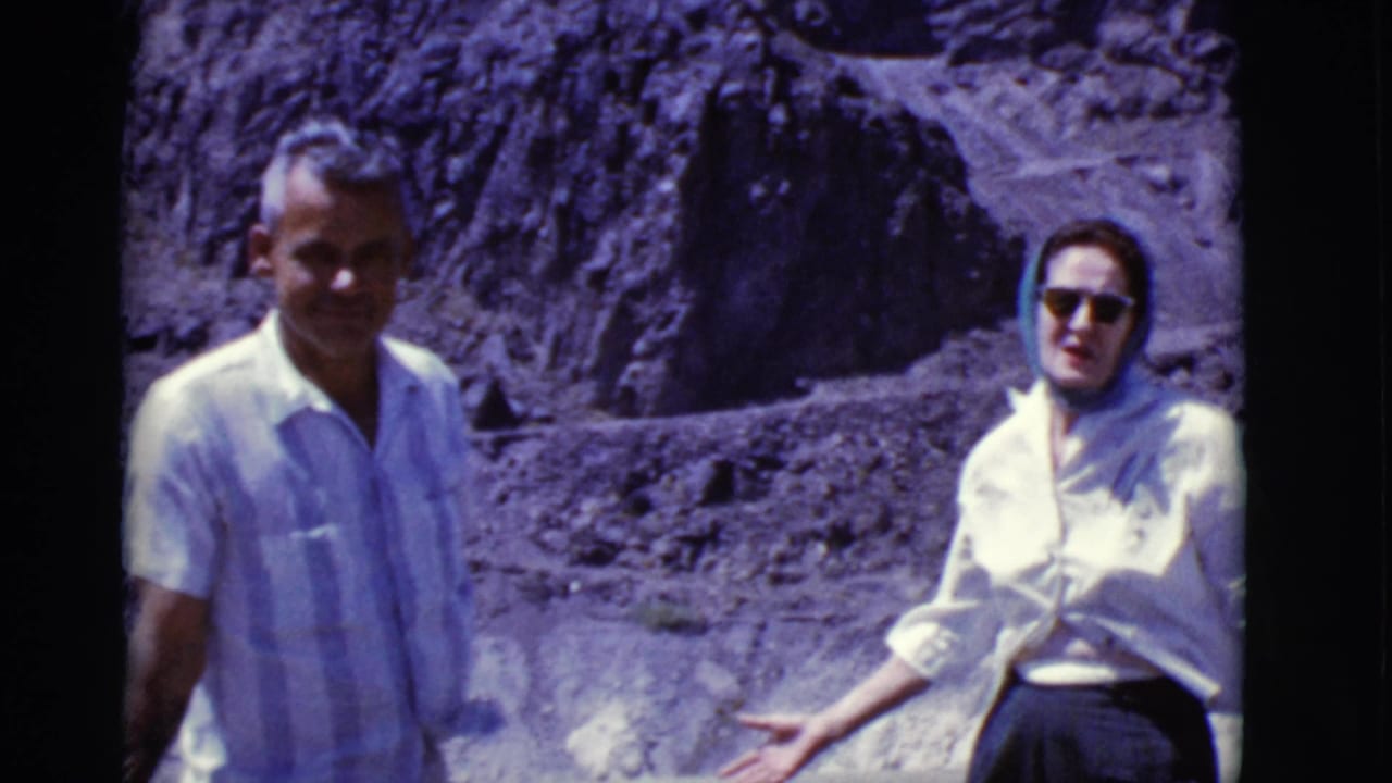 Smiling man and woman standing before rocky desert cliffs.