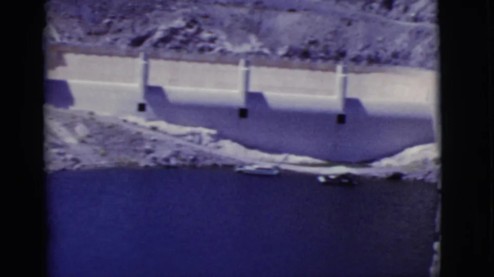The final frame shows a concrete dam wall and dark reservoir water beneath rocky Arizona desert slopes in faded 8mm color.