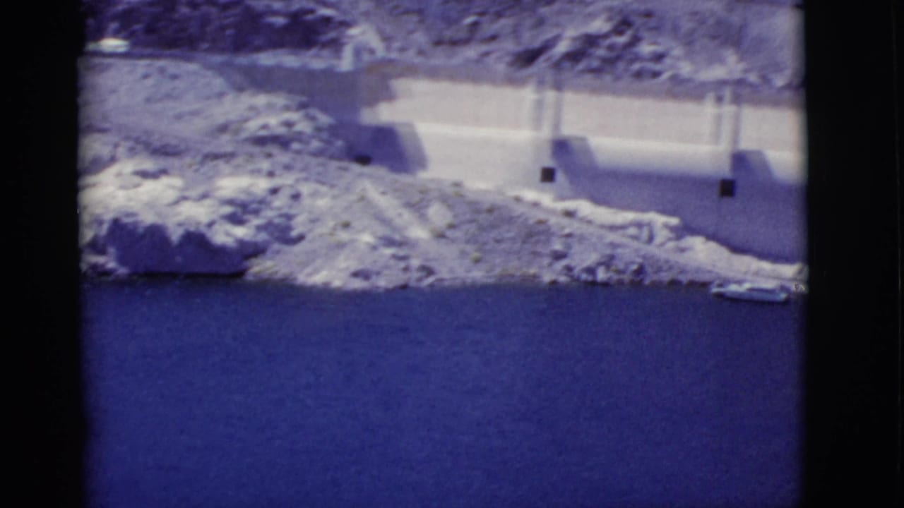 Hoover Dam wall and blue reservoir water seen from a high overlook.