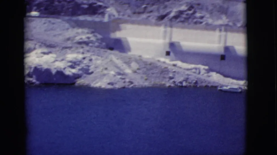 1968 Arizona travel footage showing part of Hoover Dam above deep blue Lake Mead, with rocky slopes in bright sun.