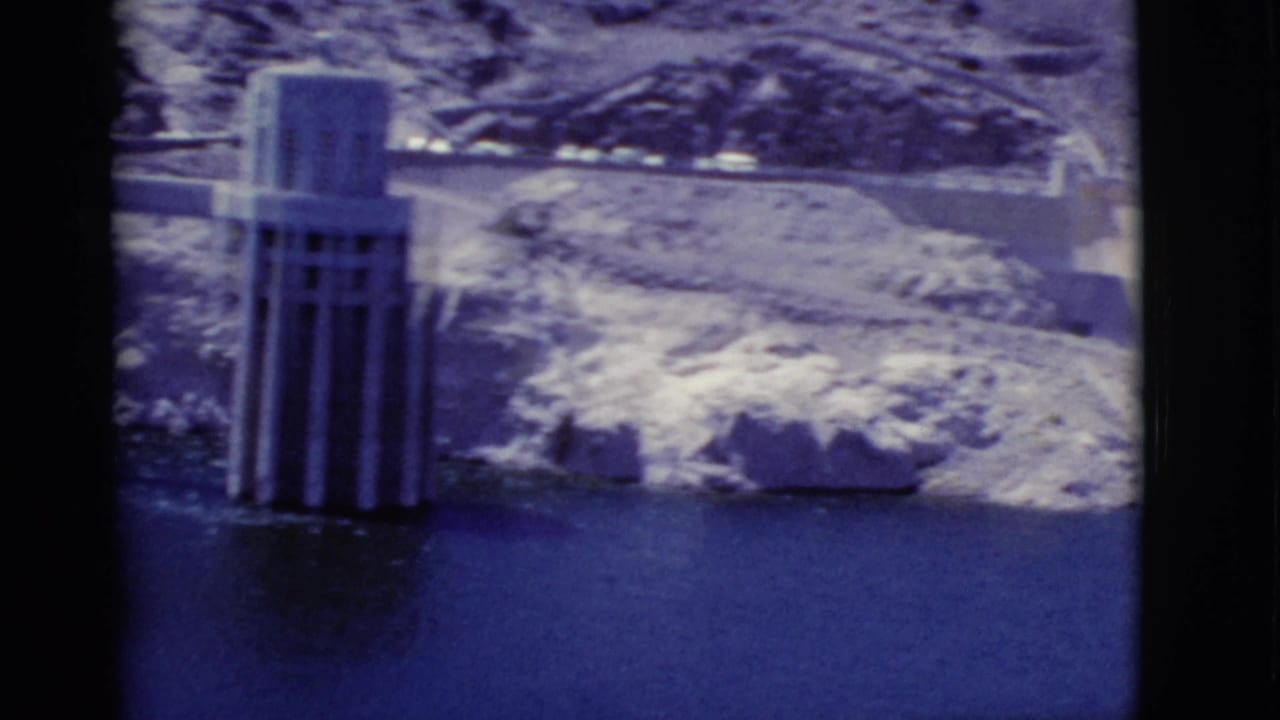 Dam intake tower and reservoir water with rocky shoreline behind it.