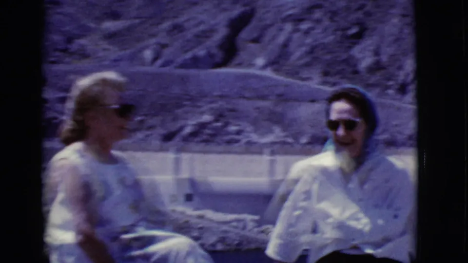 1968 Arizona home-movie frame of two adults seated together outdoors, softened by motion and 8mm focus.