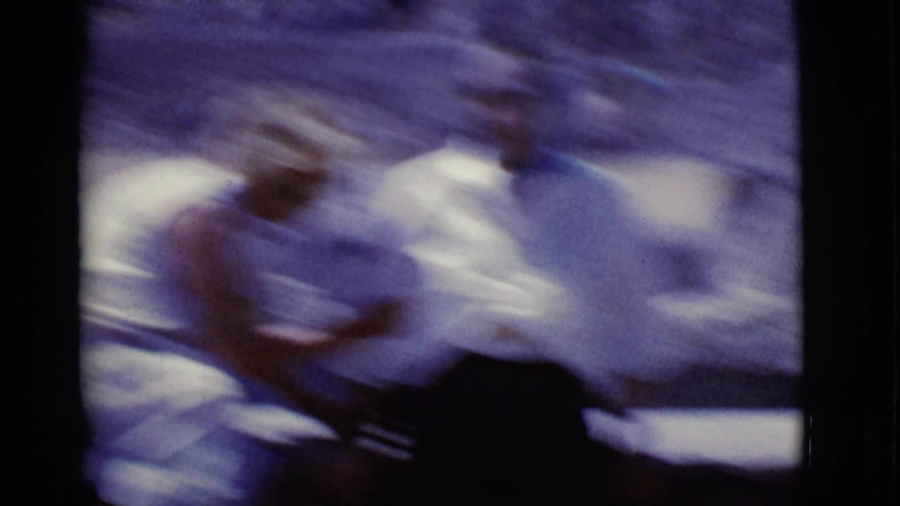Blurred handheld shot of two women seated outdoors in bright clothing.