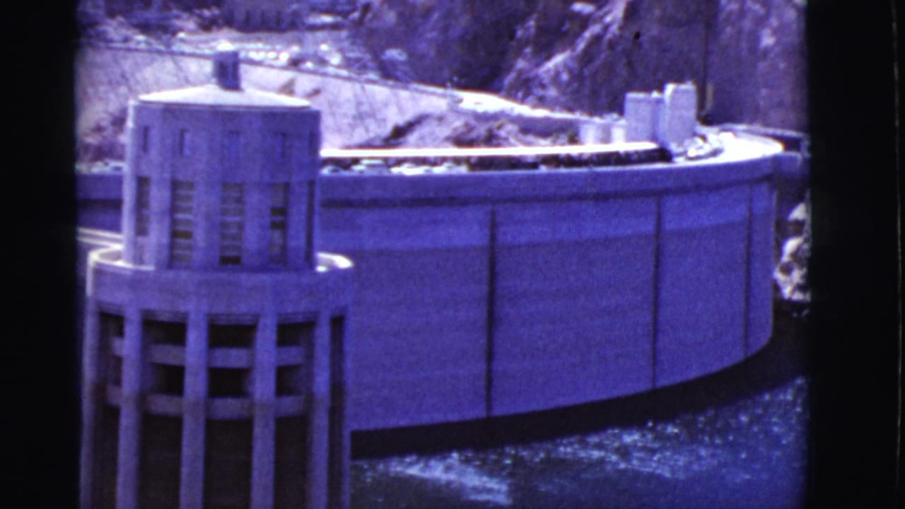 Closer view of the dam model tower beside a curved concrete wall.