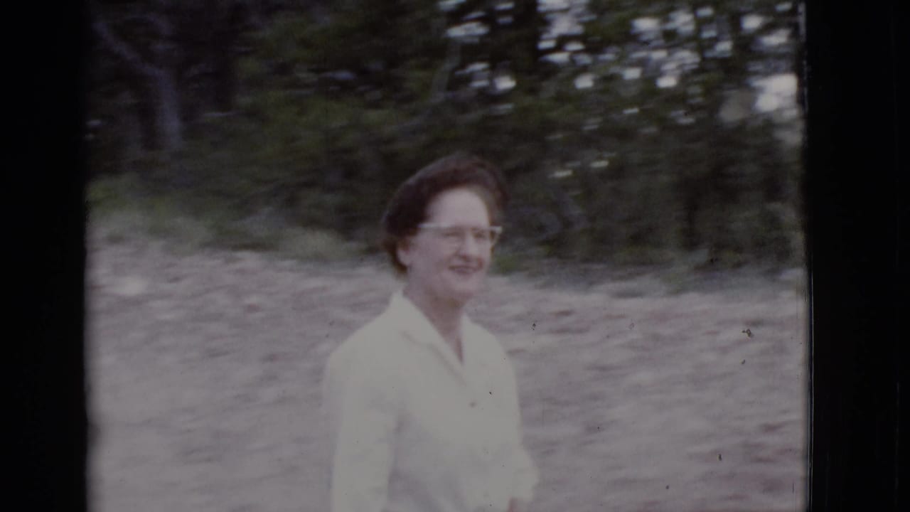 Woman in a light blouse walks along a dirt path with trees behind her.