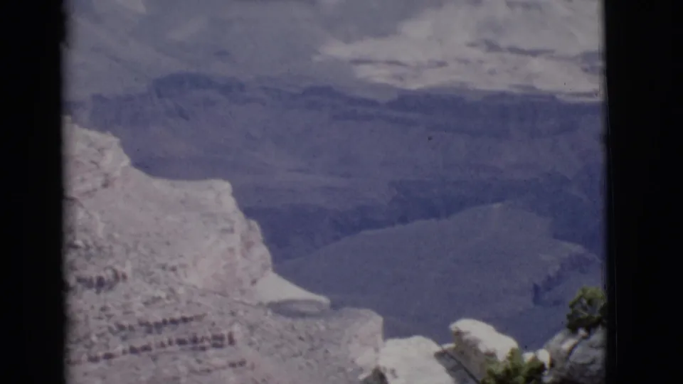1968 Arizona 8mm footage shows a snow-bright cliff face, deep canyon basin, and soft distant terrain under uneven exposure.