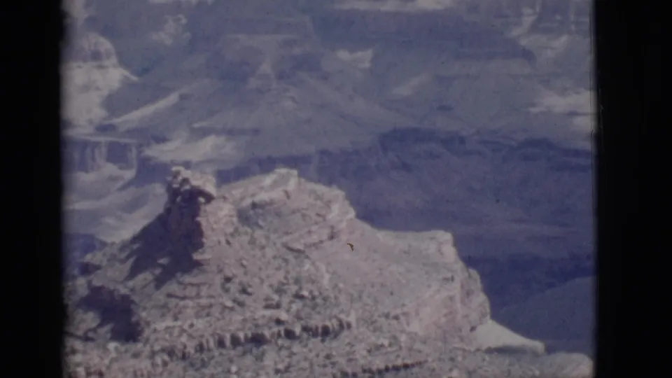 1968 Arizona 8mm frame showing layered Grand Canyon rock formations and distant canyon walls with soft color shift.