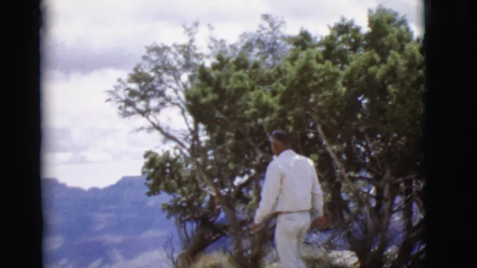 The 1968 Arizona scene shows the man moving along the overlook, framed by trees and hazy blue mountains.