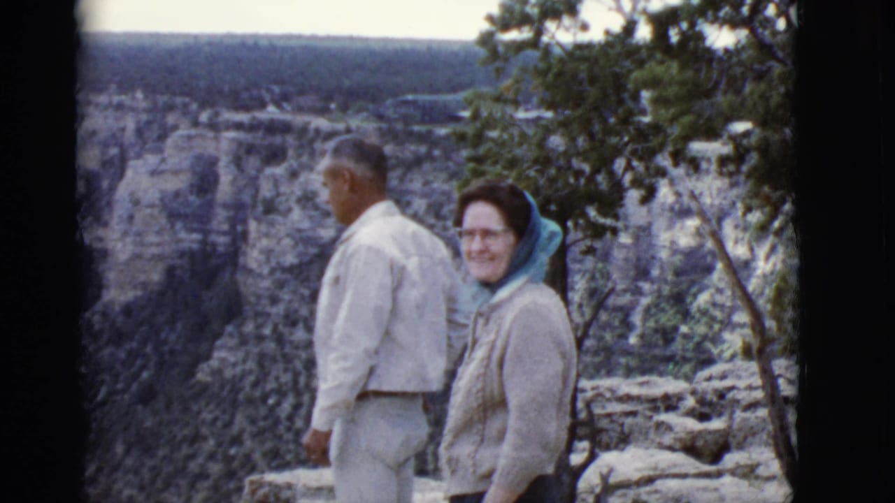 Couple at the canyon rim, with the woman smiling toward the camera and cliffs behind them.