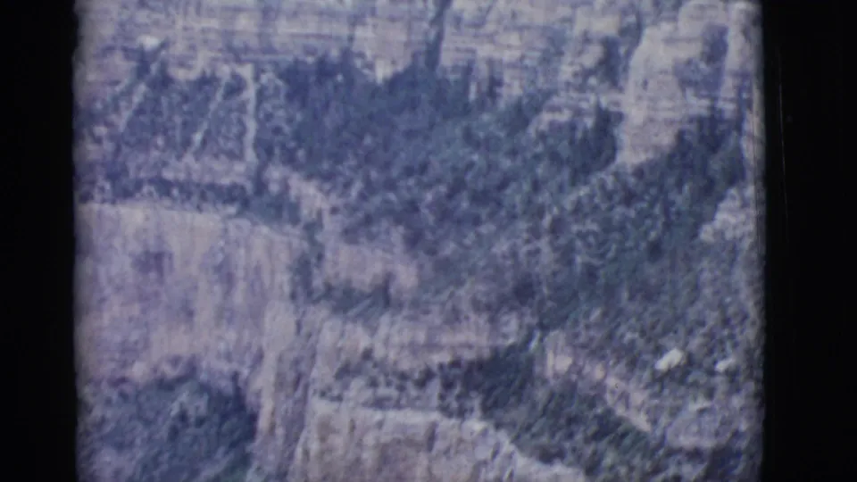 Home-movie frame from the Grand Canyon showing layered rock walls and shadowed vegetation during a brief landscape pan.