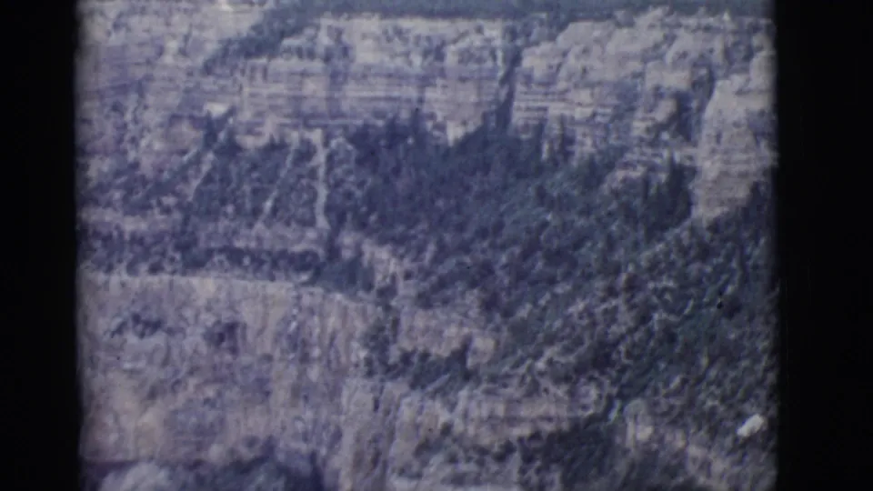 1968 Arizona home-movie landscape frame of the Grand Canyon, with pale rock layers and darker vegetation in the ravine.