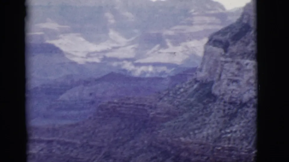 Arizona 8mm home-movie frame from 1968 showing hazy canyon depth, pale rock strata, and a cliff edge in blue-purple film color.