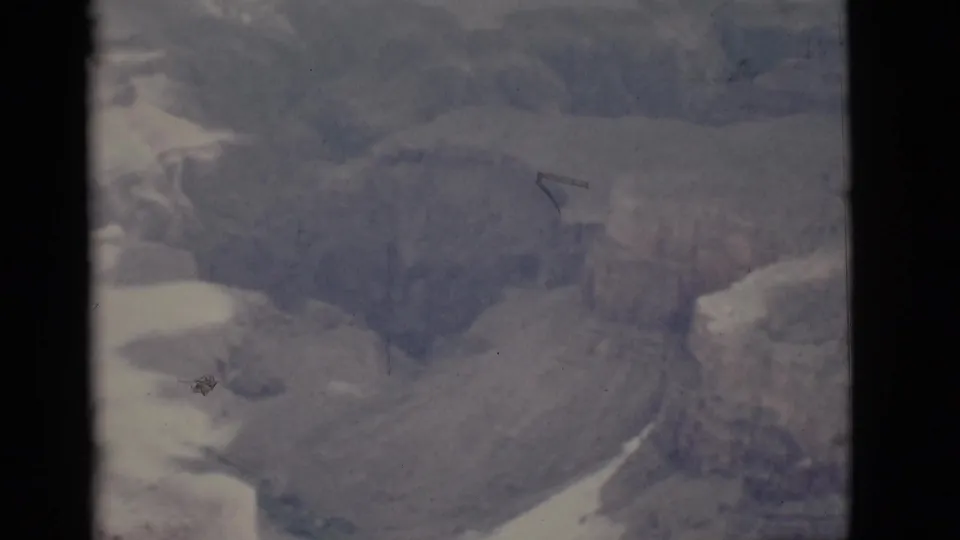 Faded 1968 8mm frame showing a hazy Arizona canyon view with layered cliffs and handheld framing.