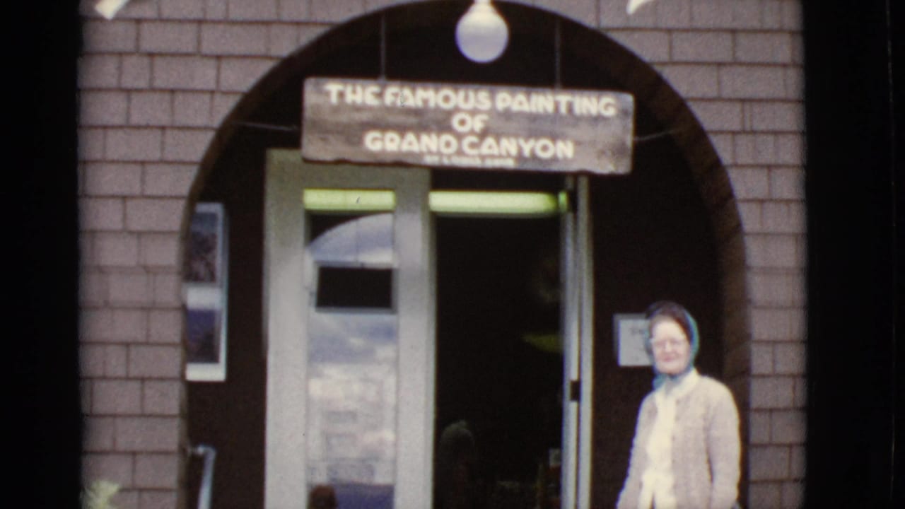 Woman standing beneath a sign for the famous painting of Grand Canyon at a brick entrance.