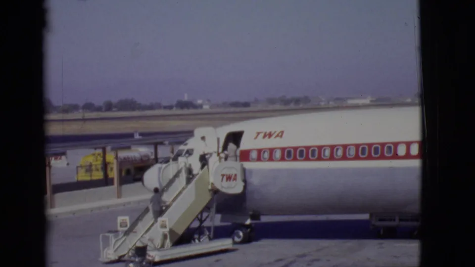 Home-movie view of a TWA jet and mobile boarding stairs as a passenger climbs toward the aircraft door in Arizona, 1968.