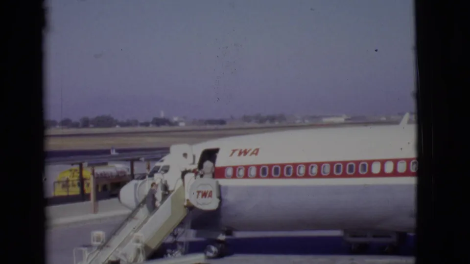 1968 Arizona airport view of a TWA jet as passengers board by mobile stairs on the tarmac.