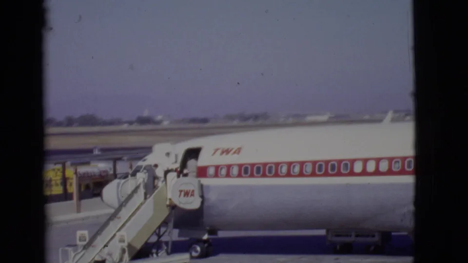 Home-movie frame of a 1968 TWA boarding scene with the aircraft fuselage filling most of the view.