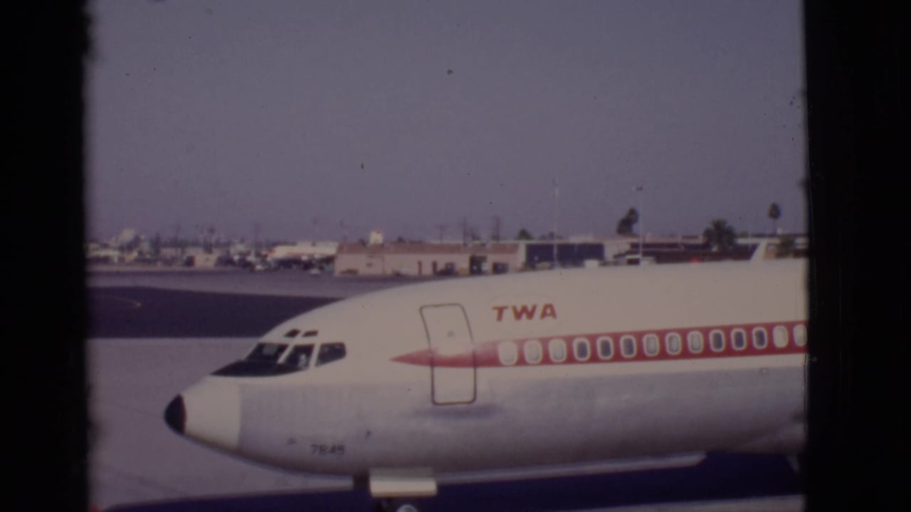 Close view of the front of a TWA airliner on an airport ramp.