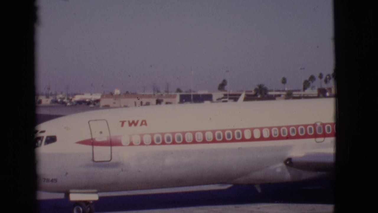 TWA aircraft nose and fuselage passing on an airport apron.
