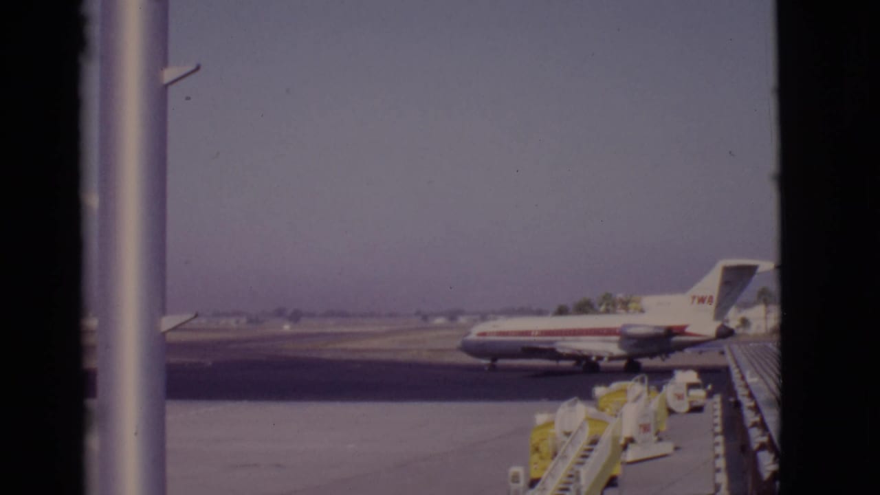 TWA jet on an airport apron viewed through dark window frames.