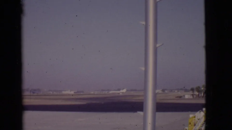 Late in the 1968 Arizona airport shot, the runway opens up as the aircraft moves out of view, leaving window framing and service equipment visible.