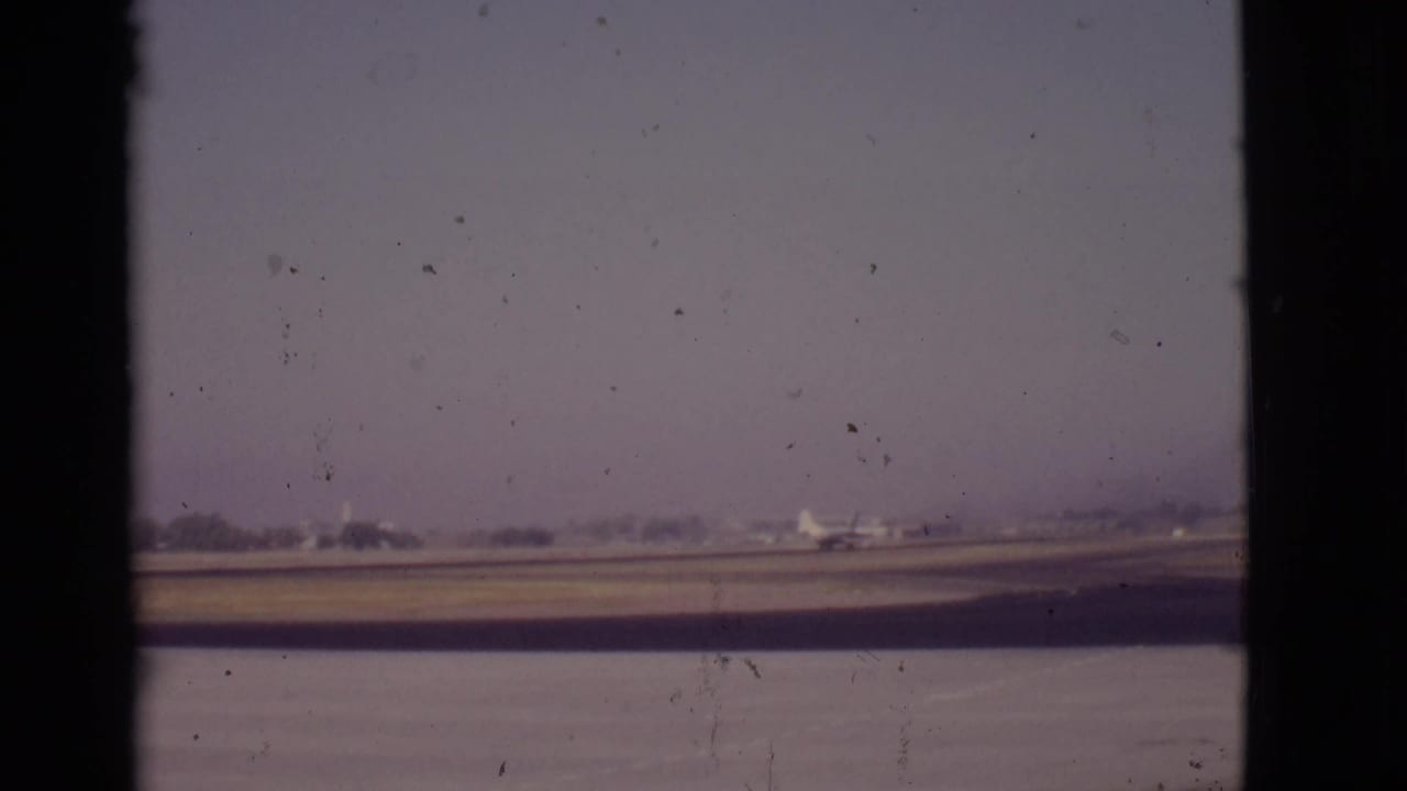 Airplane farther along the runway, framed by a central dark window divider.