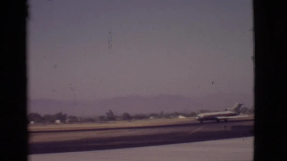 1968 Arizona airport view of a small passenger plane moving rightward on the runway, framed by dark vertical borders.