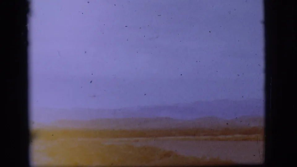 1968 8mm home-movie view near Flagstaff, Arizona, showing a distant airfield landscape with water, hills, pale sky, and film-frame borders.