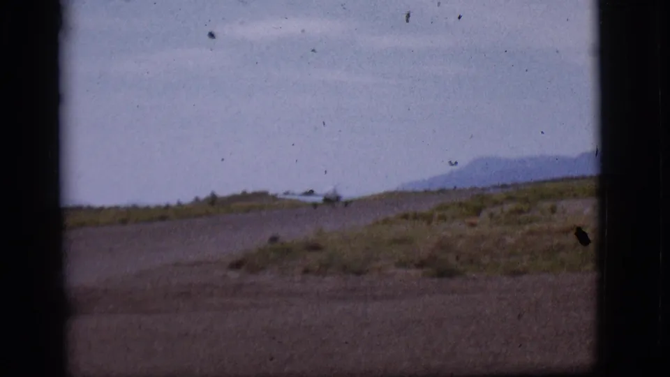 Small single-engine plane appears on a remote Flagstaff runway in 1968 home-movie footage, partly blocked by a dark window or film edge.