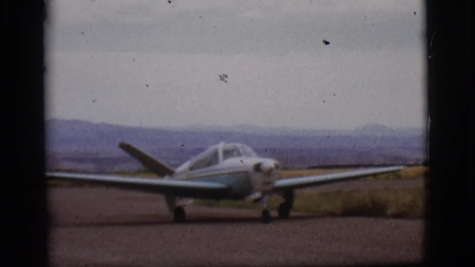 The aircraft fills more of the 8mm frame as it taxis on the Flagstaff runway, with muted hills and cloudy sky beyond.