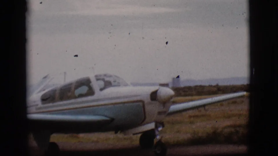 Close 8mm frame of the airplane cockpit and nose as the small aircraft taxis past in Flagstaff, Arizona in 1968.