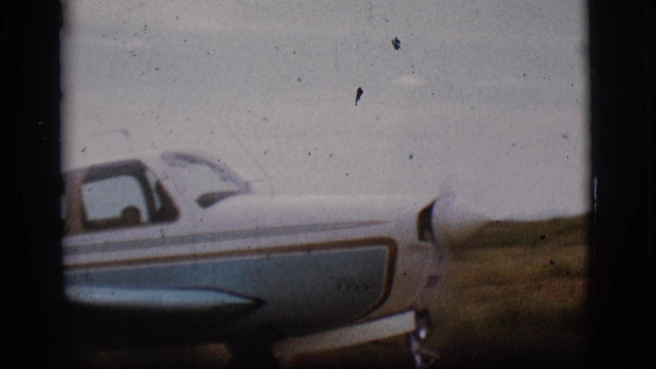 Blue and white propeller plane seen close from the side on a runway.