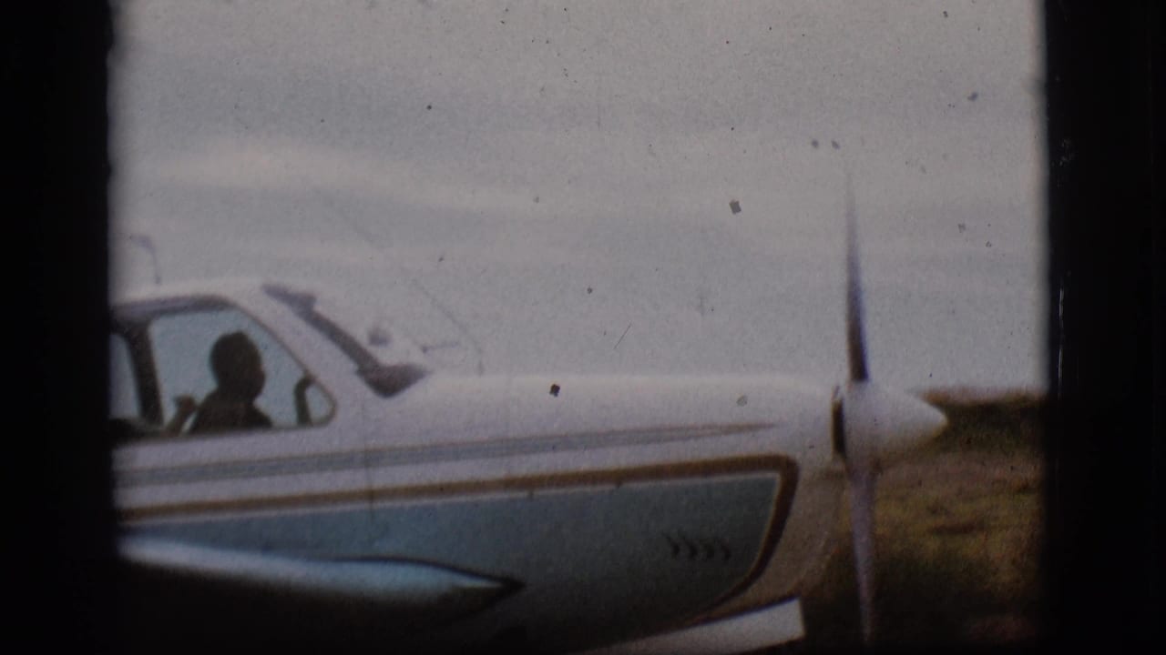 Close side view of the small aircraft cockpit in 1968 Flagstaff footage, with a person silhouetted behind the window.
