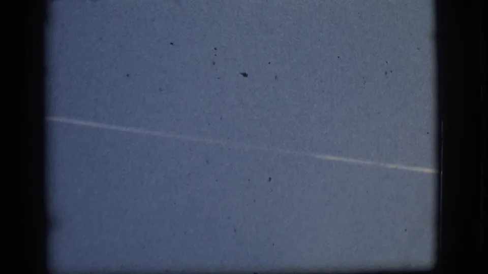 1968 Flagstaff-attributed 8mm frame showing a faint white streak across a pale blue sky with visible dust and gate edges.