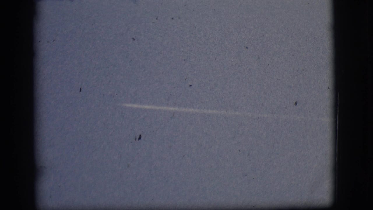 Blue sky with a faint white streak near the center and visible film specks.
