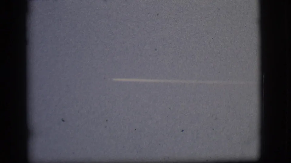 A small distant aircraft and white contrail appear against the Flagstaff sky in this 1968 8mm home-movie frame.