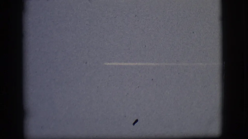 1968 Flagstaff 8mm footage shows a faint horizontal contrail low in the frame, with visible film dust and gate edges.