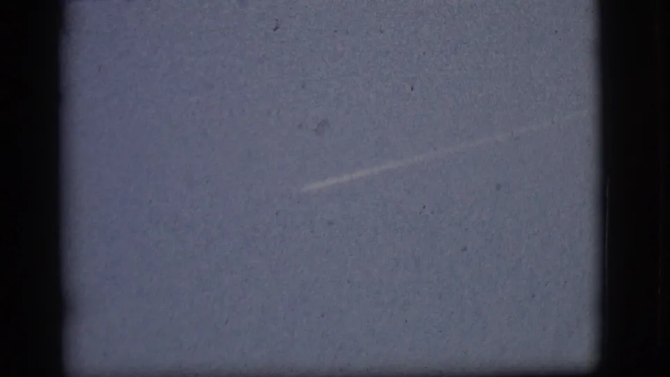 A curving section of jet contrail appears in the 1968 Flagstaff sky, framed by dark 8mm borders and visible dust.