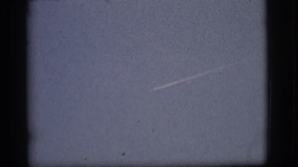 A short, angled contrail sits low in the 1968 Flagstaff sky, framed by dark 8mm borders and visible grain.