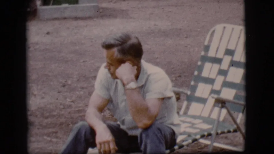A seated man in a short-sleeve shirt rests in a green and white striped lounge chair at the Flagstaff campsite.