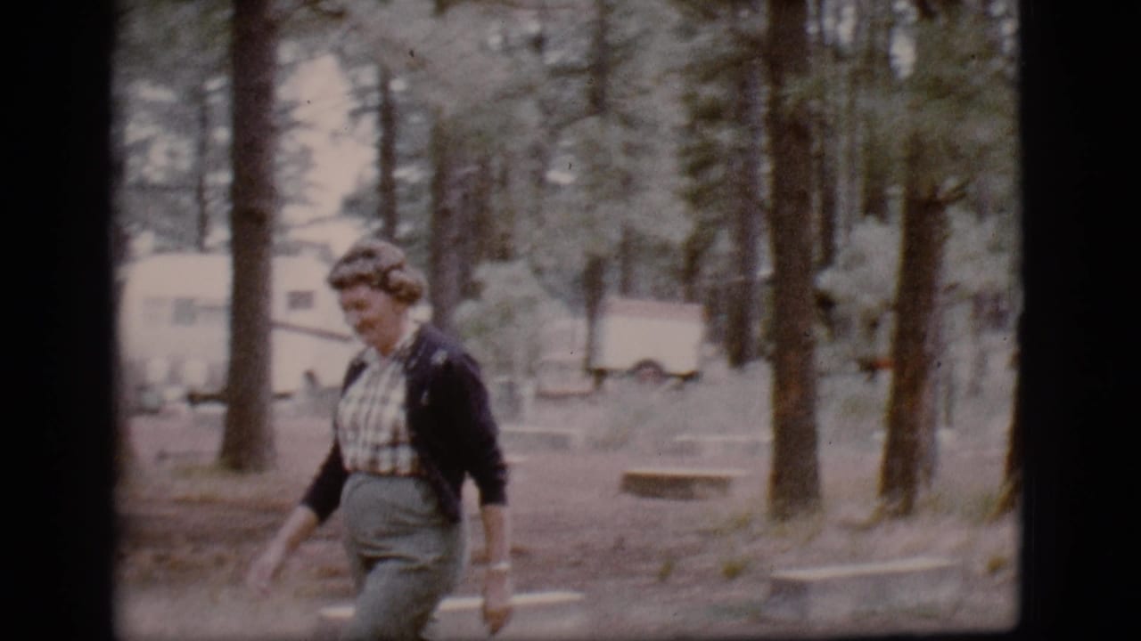 Woman smiles while walking past trees with trailers in the background.