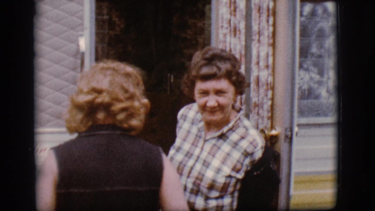 In the 1968 Flagstaff camping-trip footage, a woman in a plaid shirt smiles near the mobile home doorway while another woman faces away from the camera.