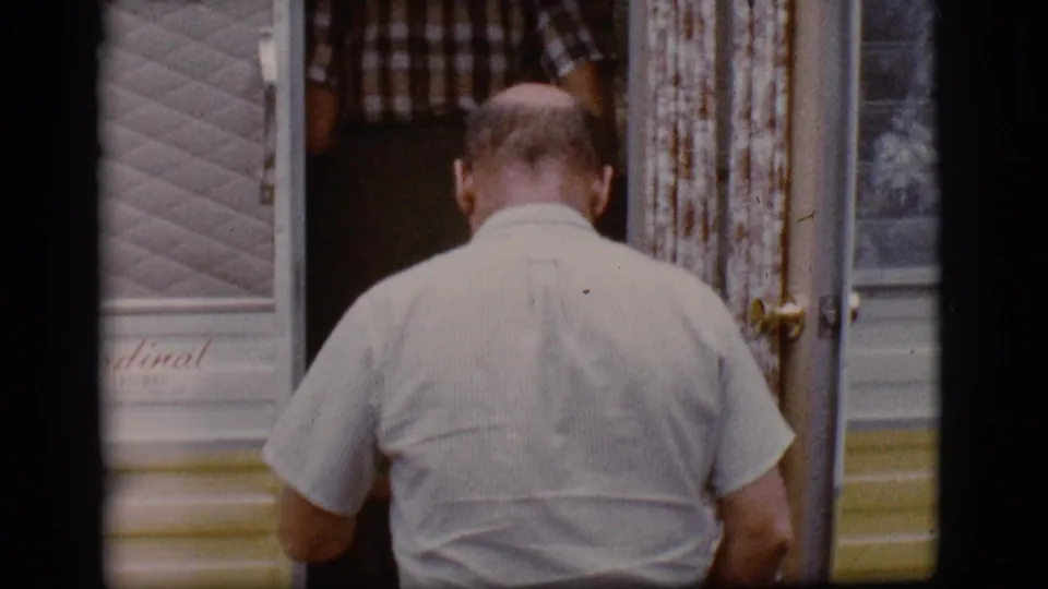 In 1968 Flagstaff home-movie footage, a balding man in light clothes steps into a travel trailer at a campground.