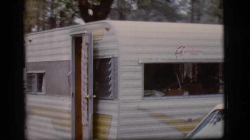 The camper trailer remains at the wooded Flagstaff campsite, with a partial vehicle edge entering the lower right frame.
