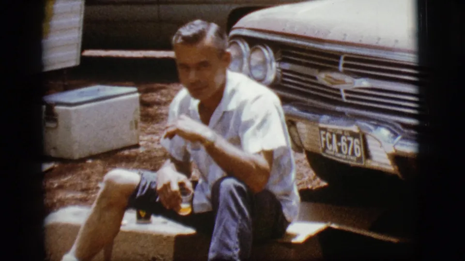 In the final frame, the adult man raises a glass in a toast-like gesture beside the Chevrolet and white cooler.