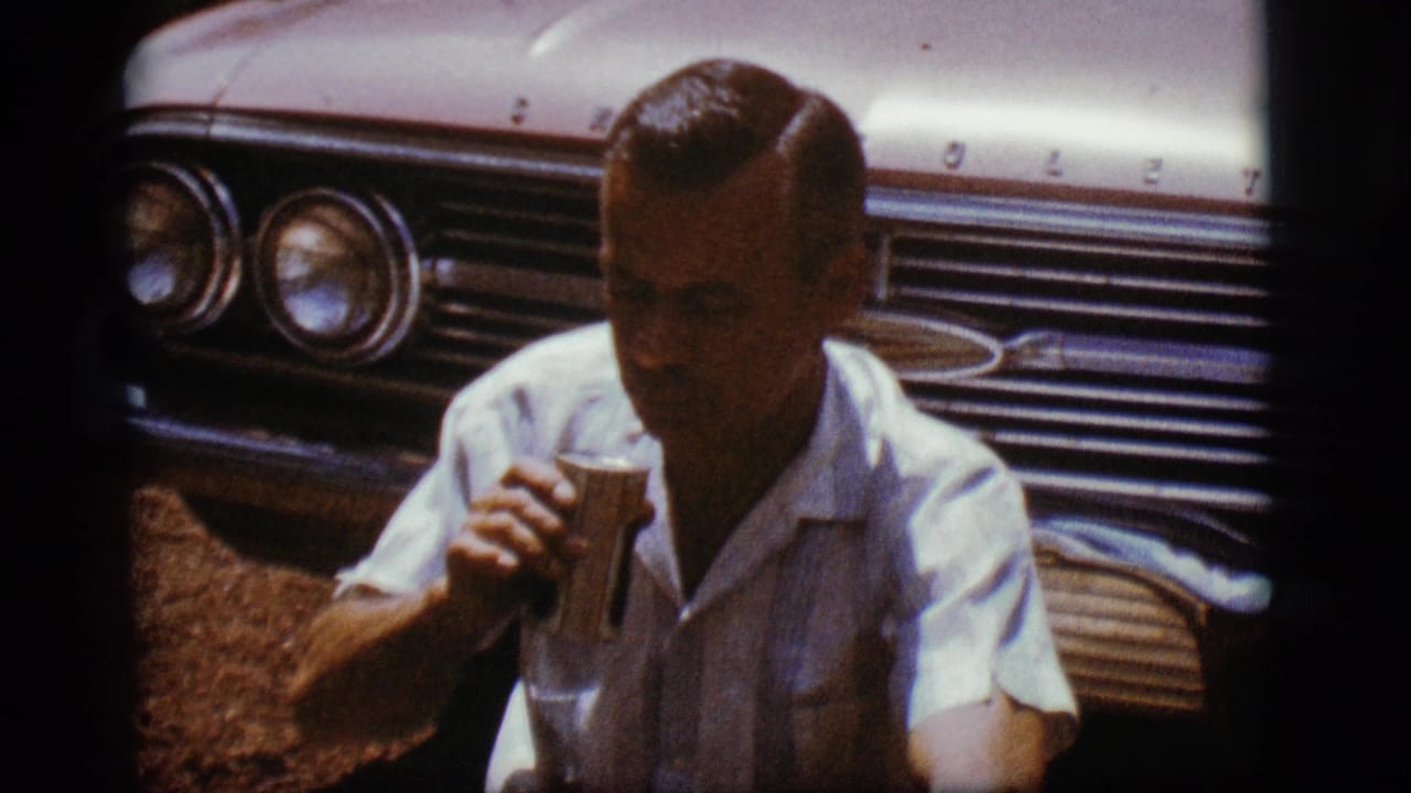 Man holding a can in front of a Chevrolet grille and headlights.