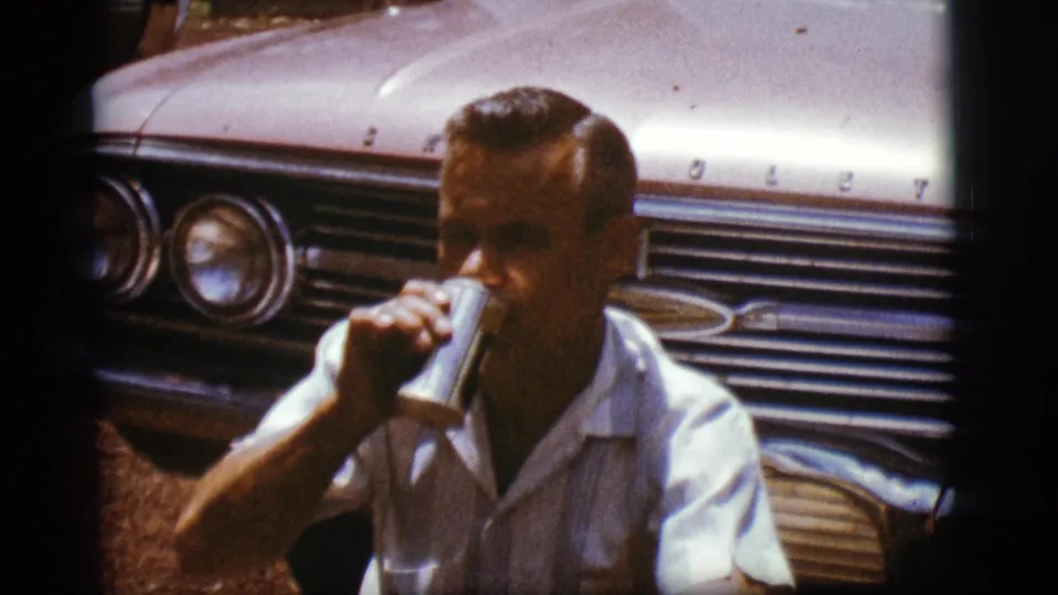 In the final frame, the man lifts the can to drink while seated beside the Chevrolet at an outdoor stop.