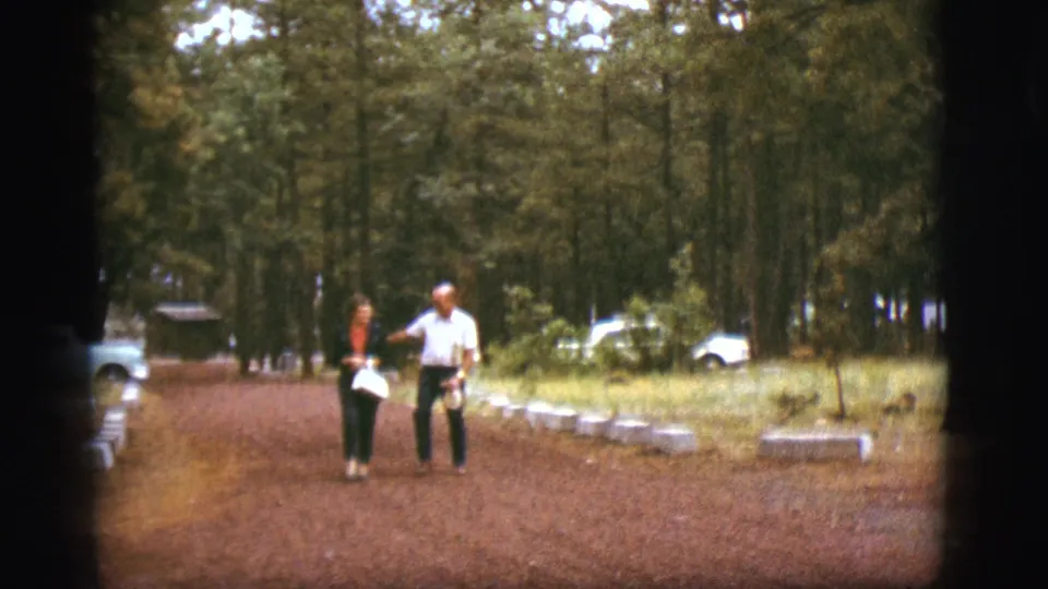 In the 1968 Flagstaff scene, the couple walks side by side on the reddish path as the man gestures and the woman holds a bag.